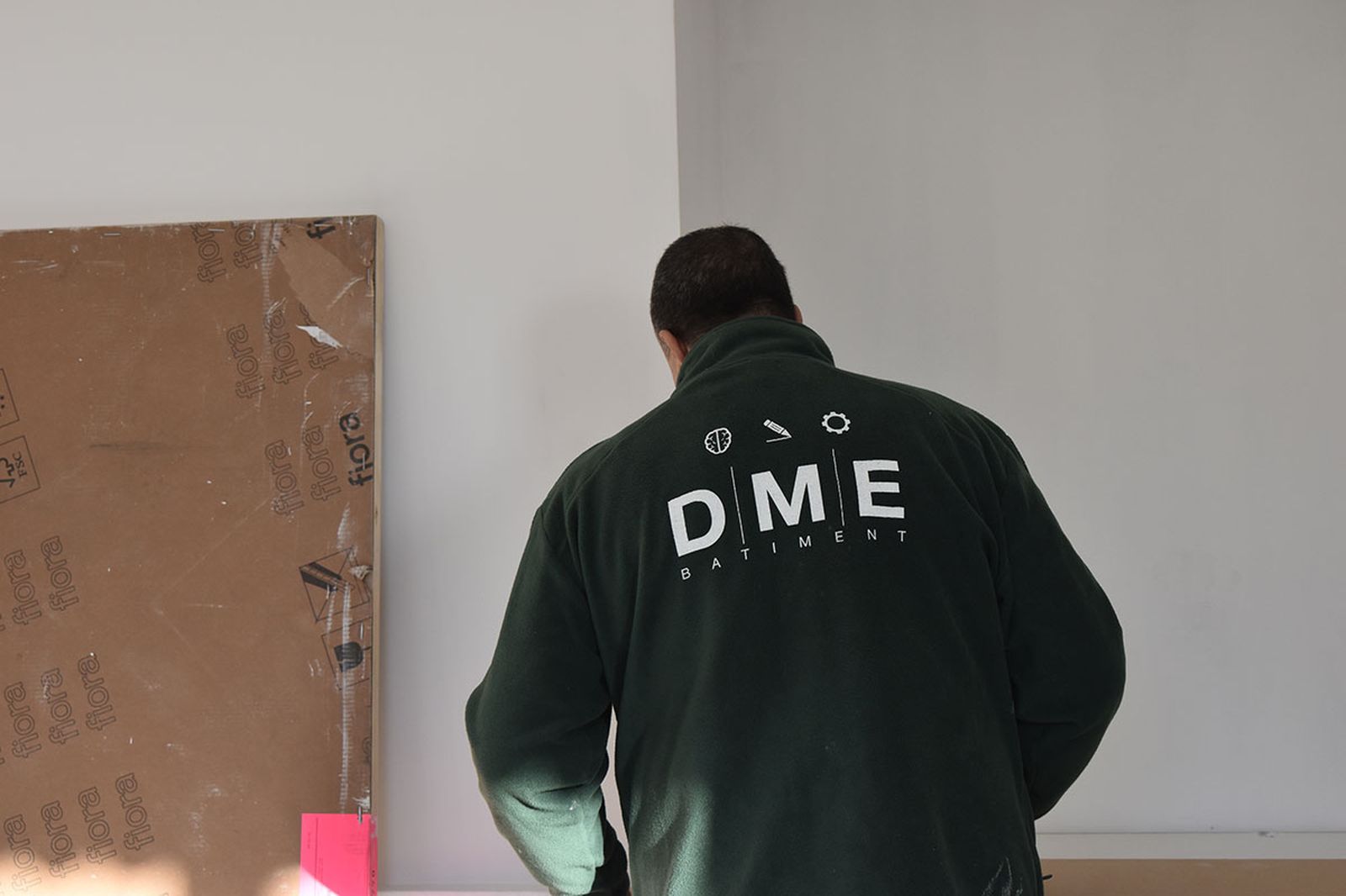 Un compagnon DME Bâtiment sur un chantier, veste floquée