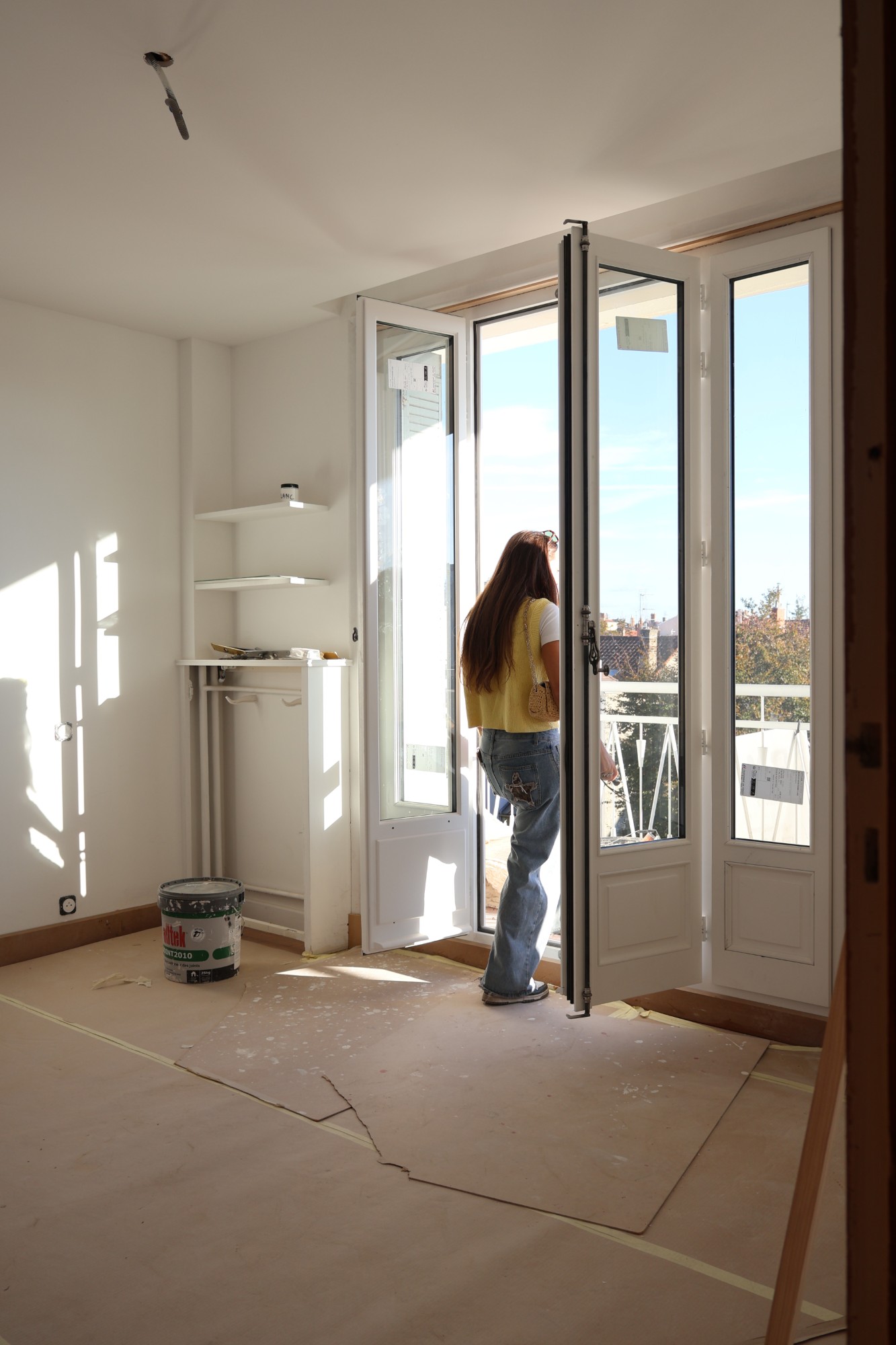Portes-fenêtres neuves posées dans un appartement en cours de rénovation, ouvertes sur un balcon