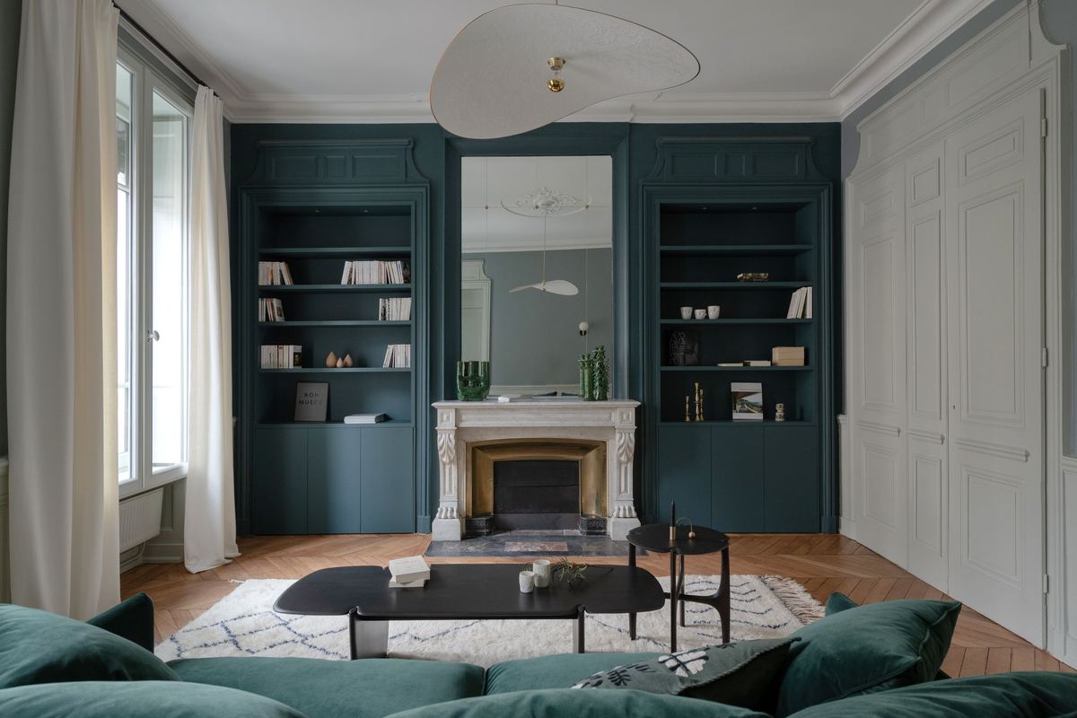 Appartement rénové par DME Bâtiment à Lyon 6e : salon avec bibliothèques sur mesure et cheminée en marbre